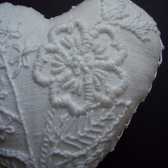 White thread embroidery on a white linen cushion.